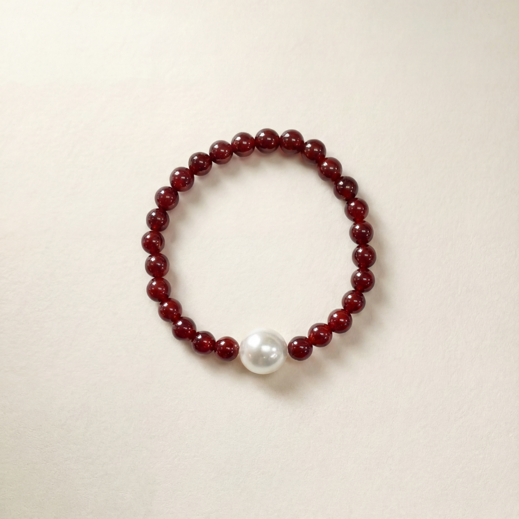 Bracelet with red beads and a white pearl on a beige background