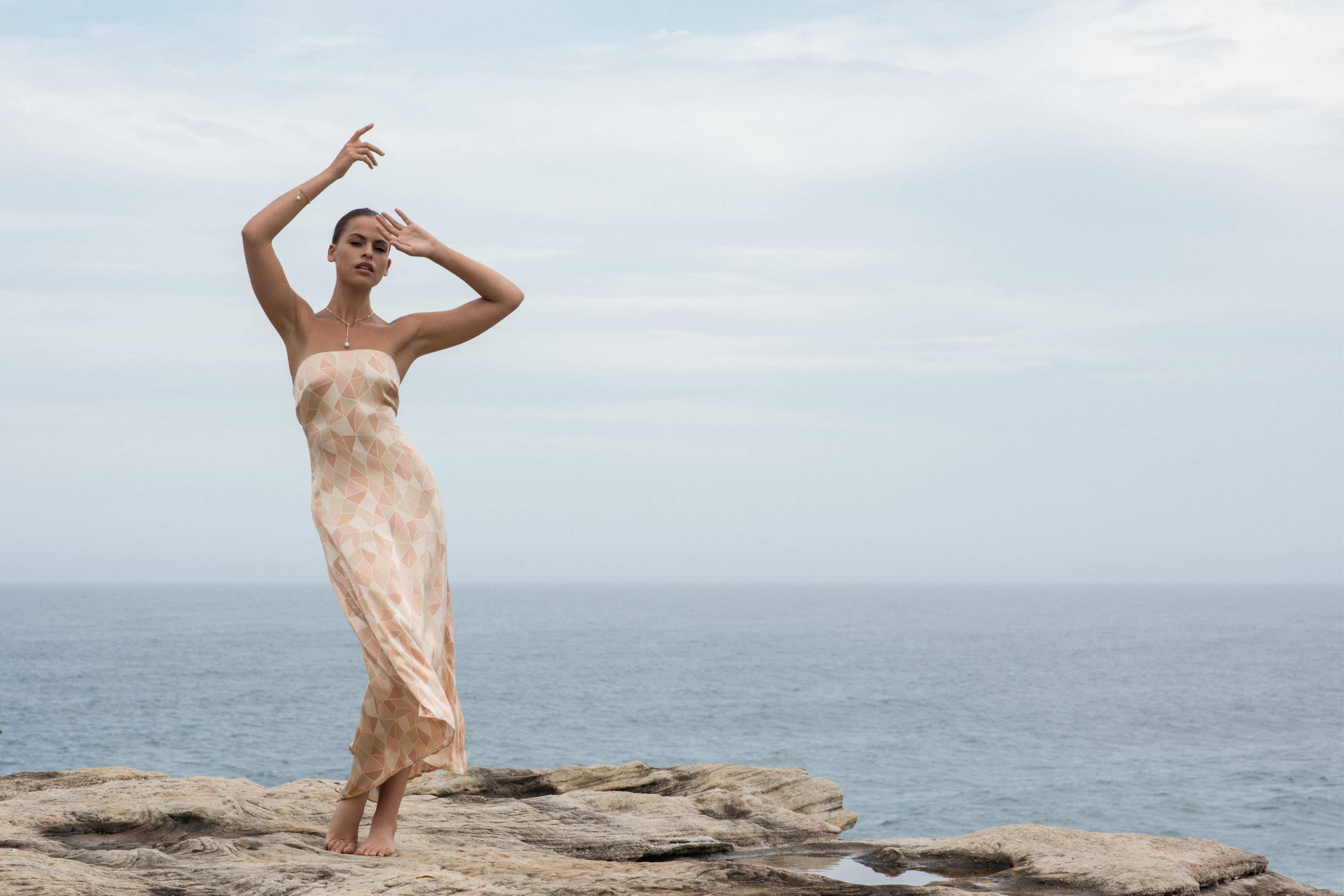 Model in a coastal setting on ocean rocks, embodying the AUTORE MODA brand aesthetic