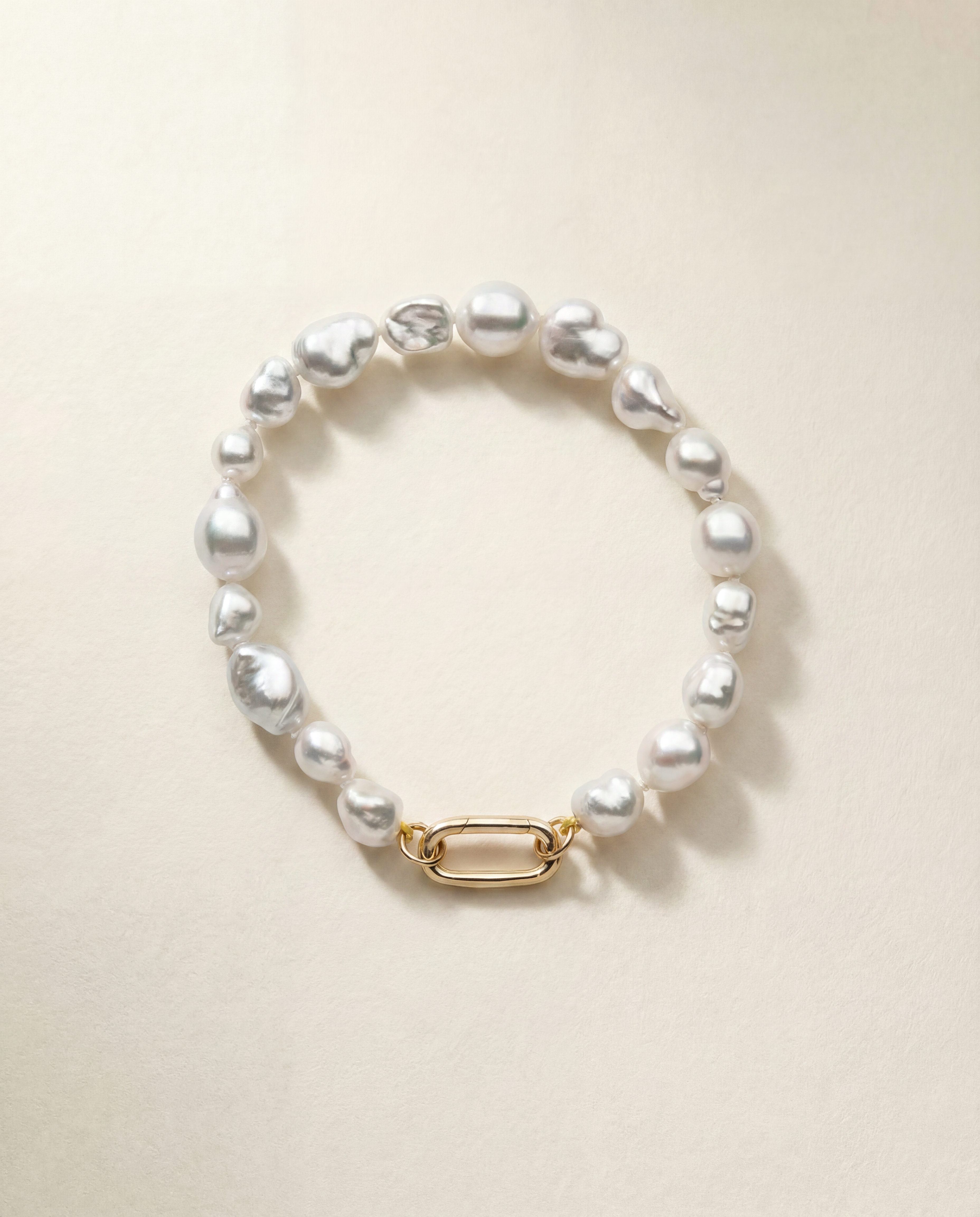Pearl bracelet with a gold clasp on a beige background