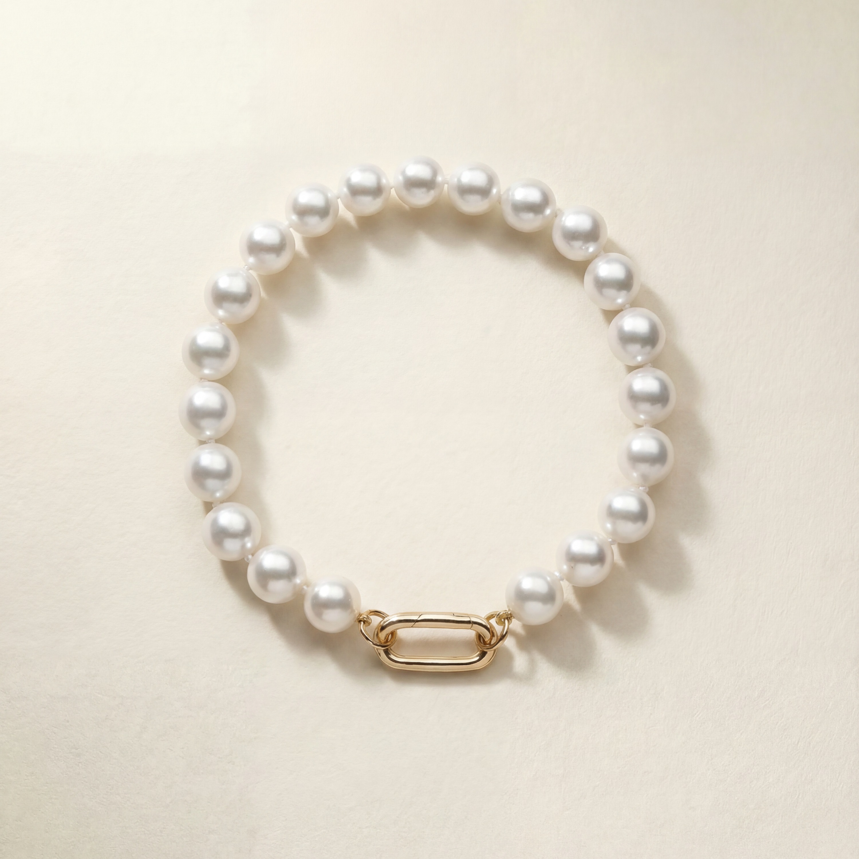 Pearl bracelet with a gold clasp on a beige background