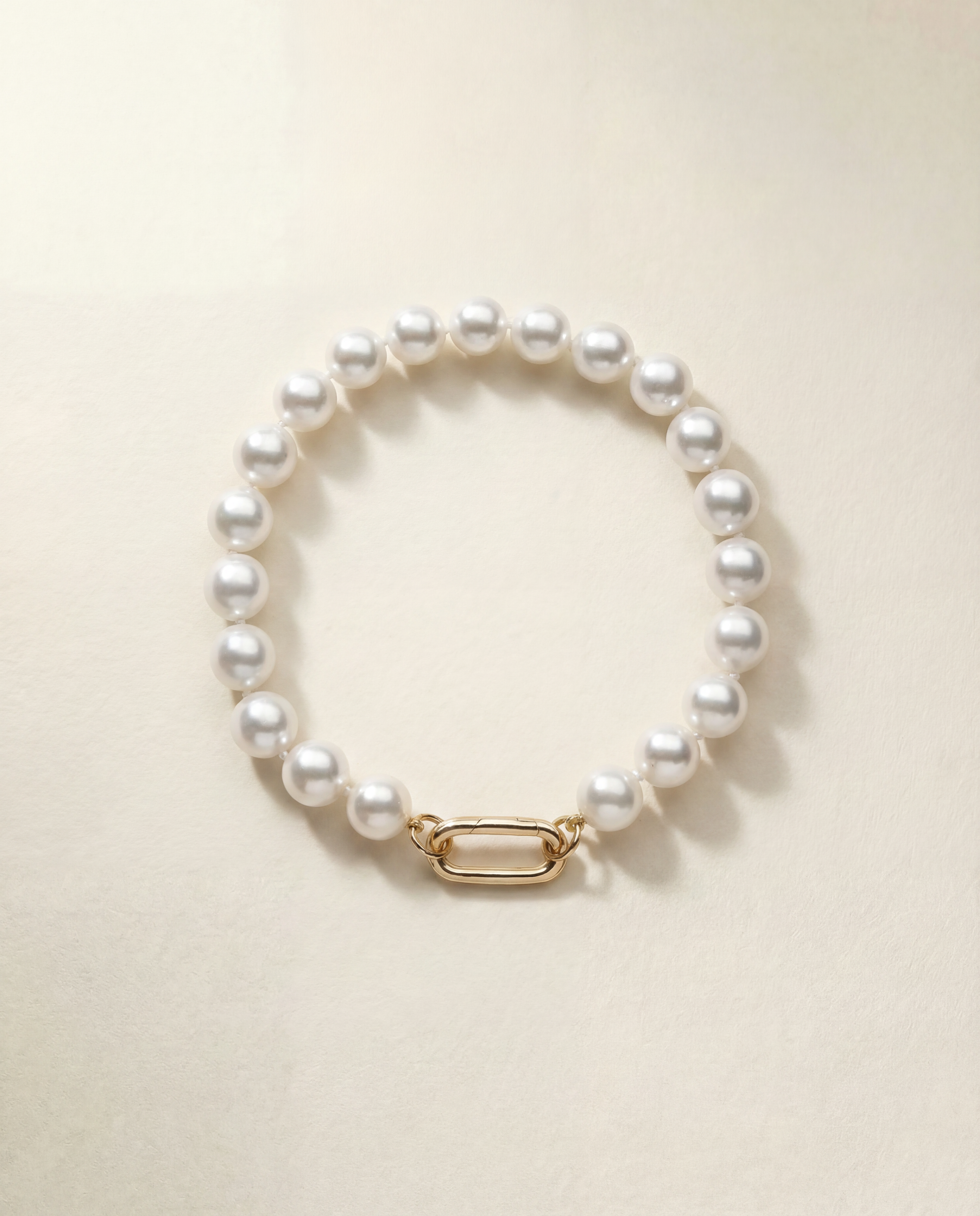 Pearl bracelet with a gold clasp on a beige background