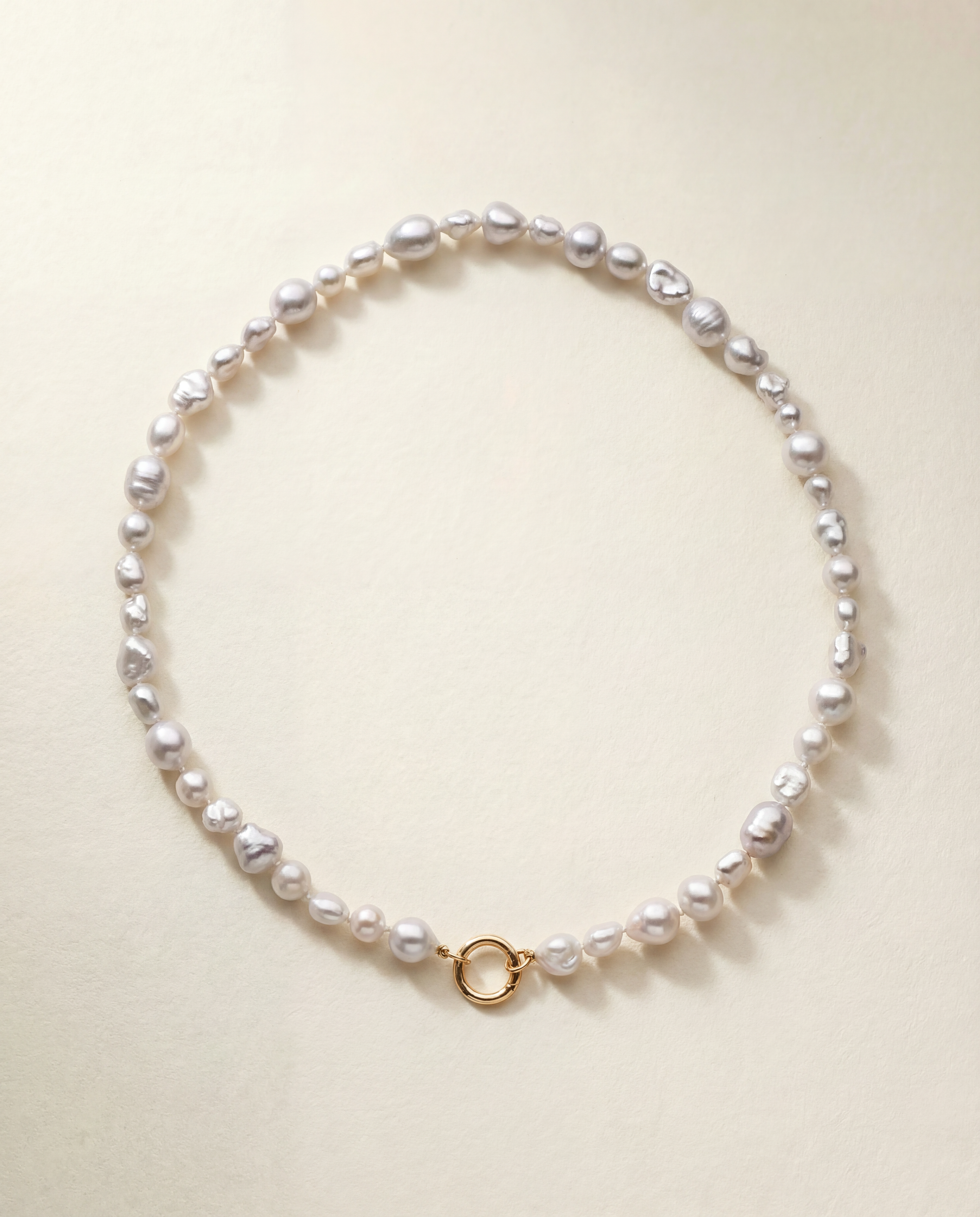 Pearl necklace with a gold clasp on a light beige background