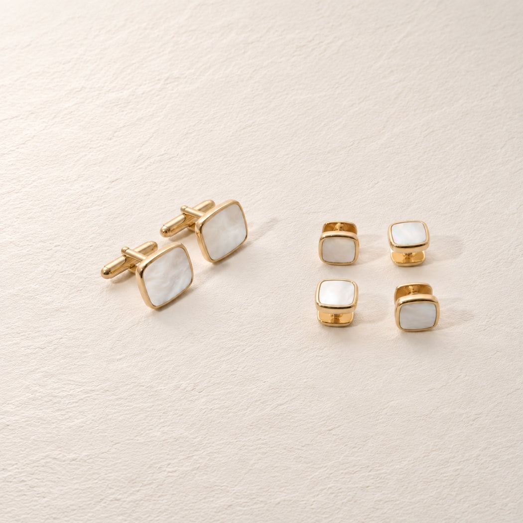 A men's formal accessories set featuring gold-tone cufflinks and matching shirt studs with square white mother-of-pearl inlays, arranged on a textured cream background.