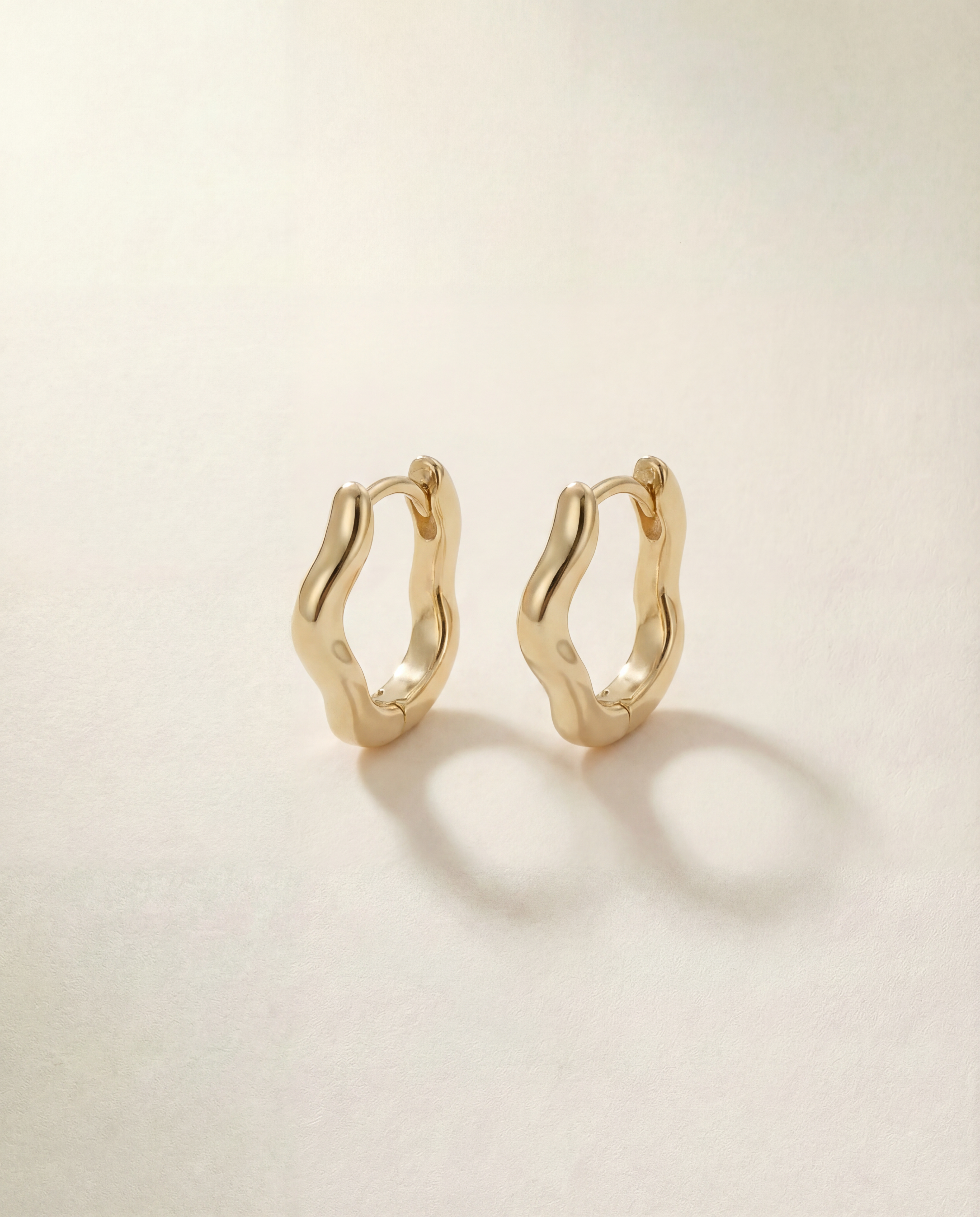 Gold hoop earrings on a light beige background