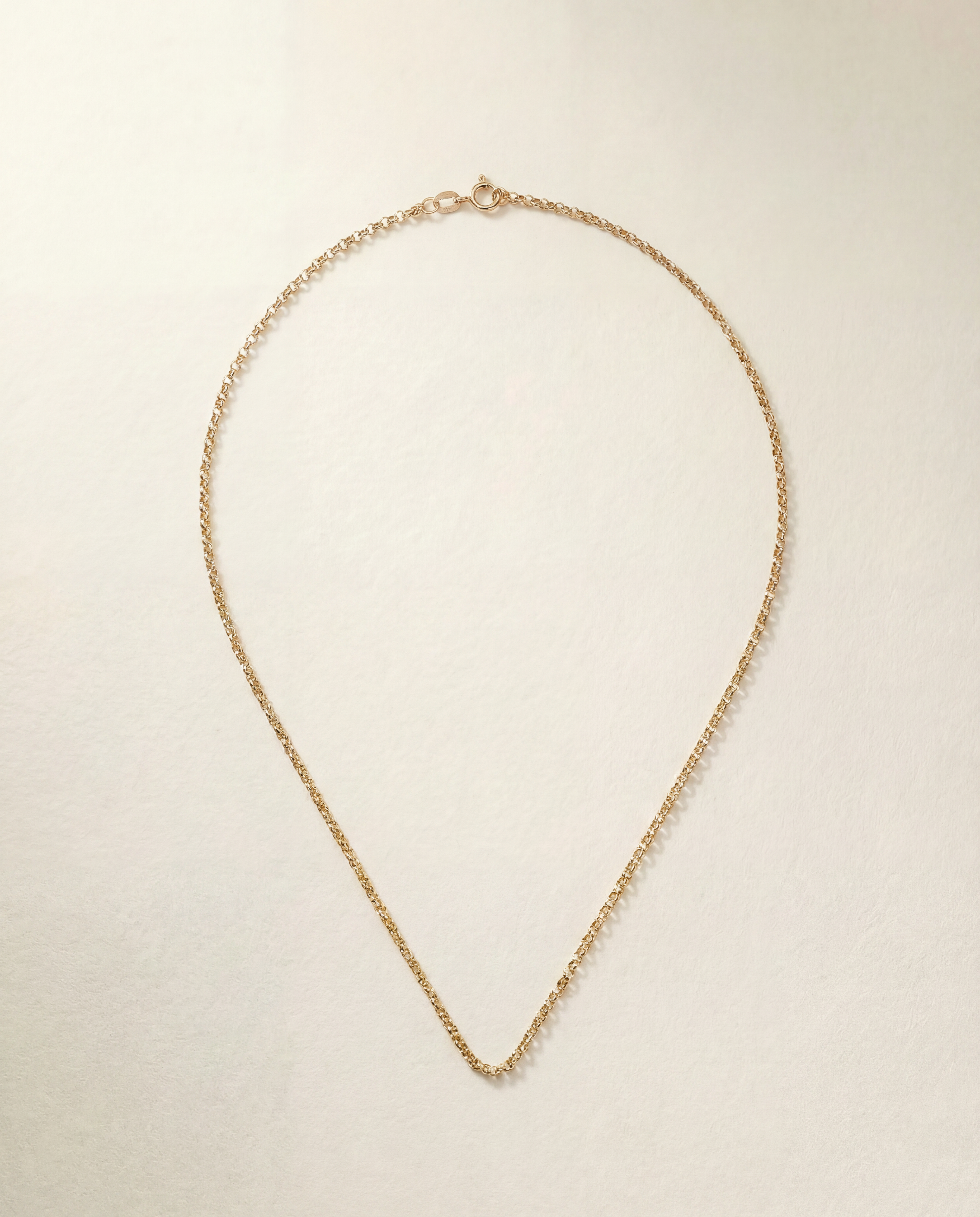 Gold chain necklace on a light beige background
