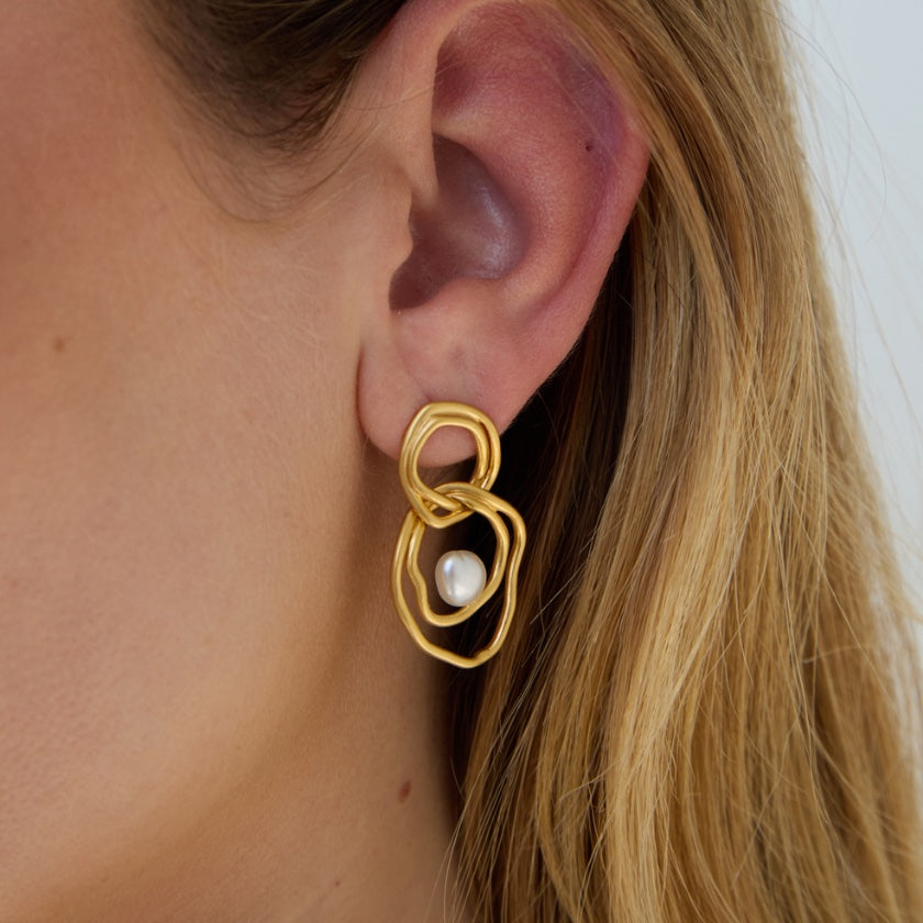 Gold earring with a pearl on an ear