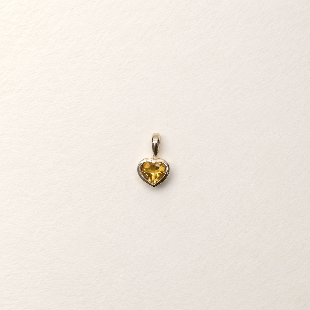 A citrine heart-shaped pendant charm, bezel set in 9k yellow gold