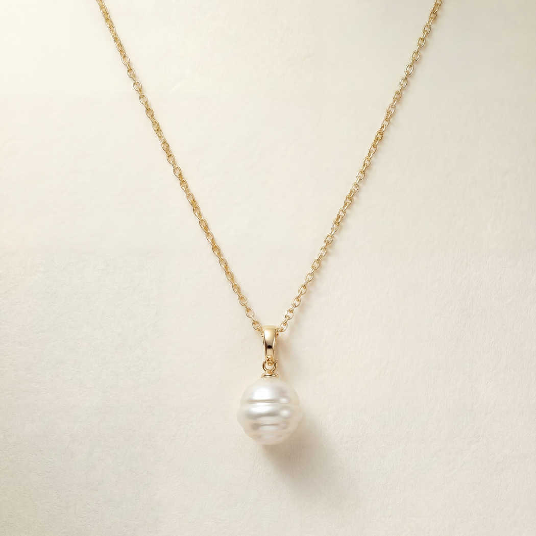 Pearl necklace with gold chain on a beige background