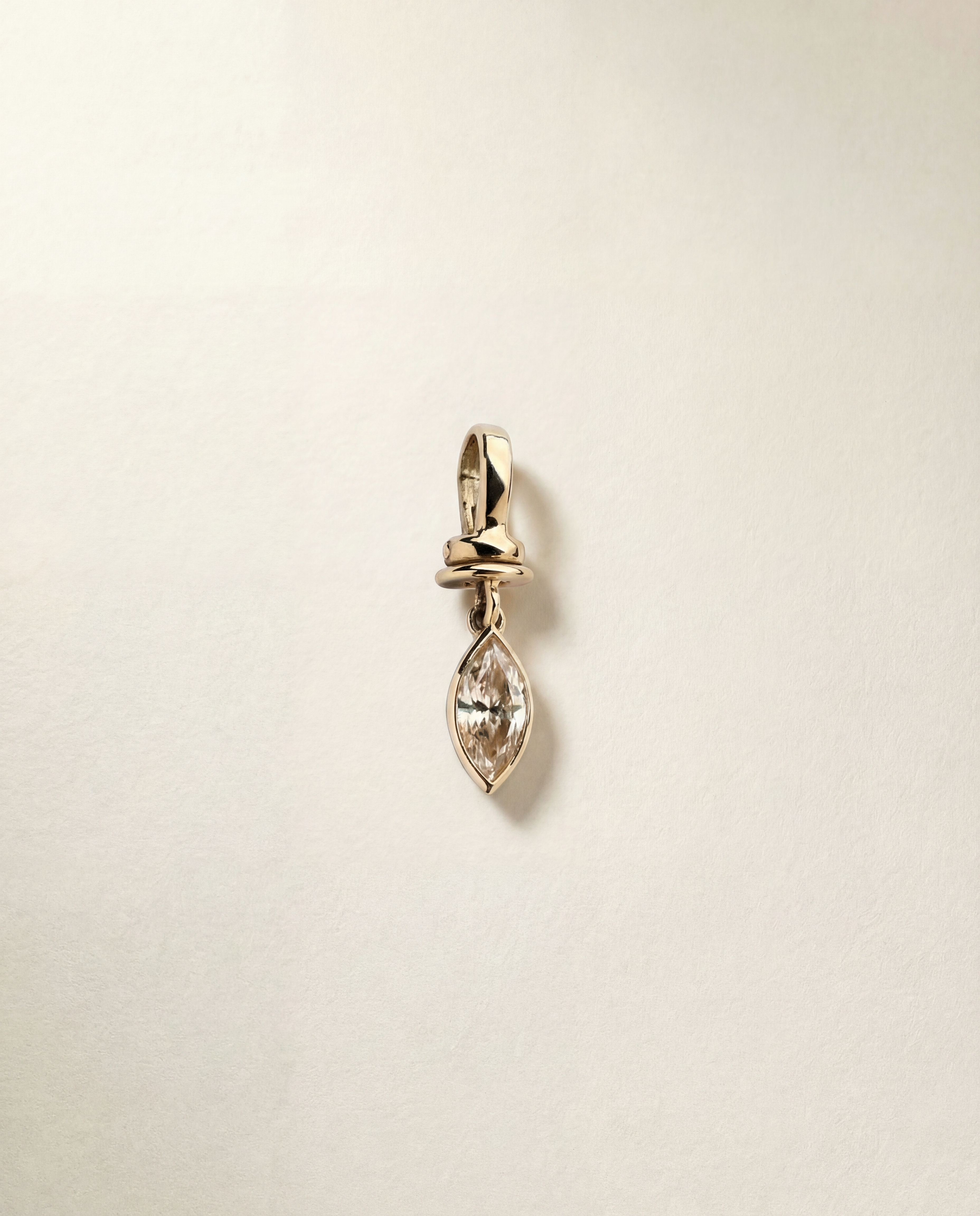 Gold pendant charm with a champagne diamond gemstone on a beige background