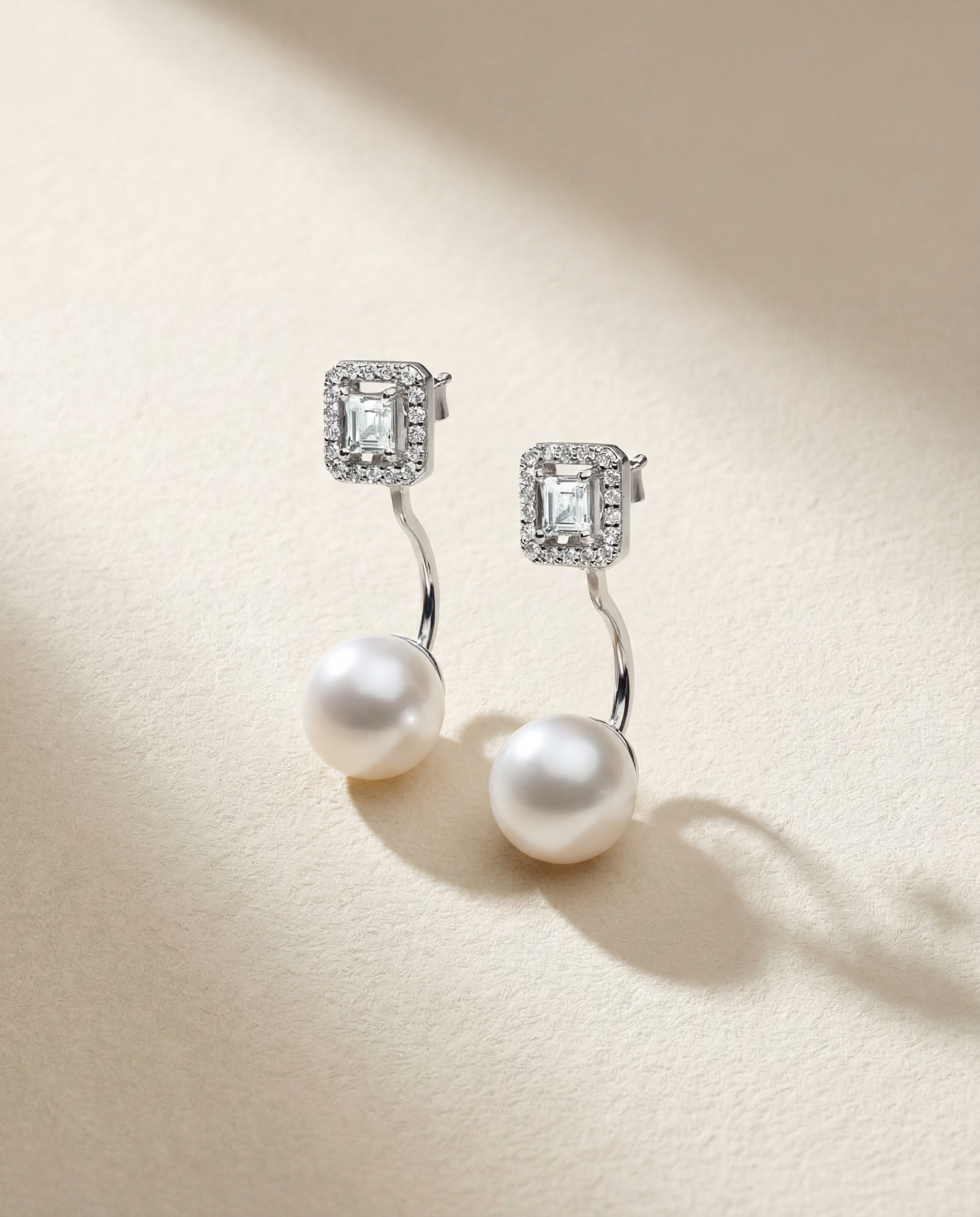 Pearl earrings with diamond-sapphire stones on a beige background