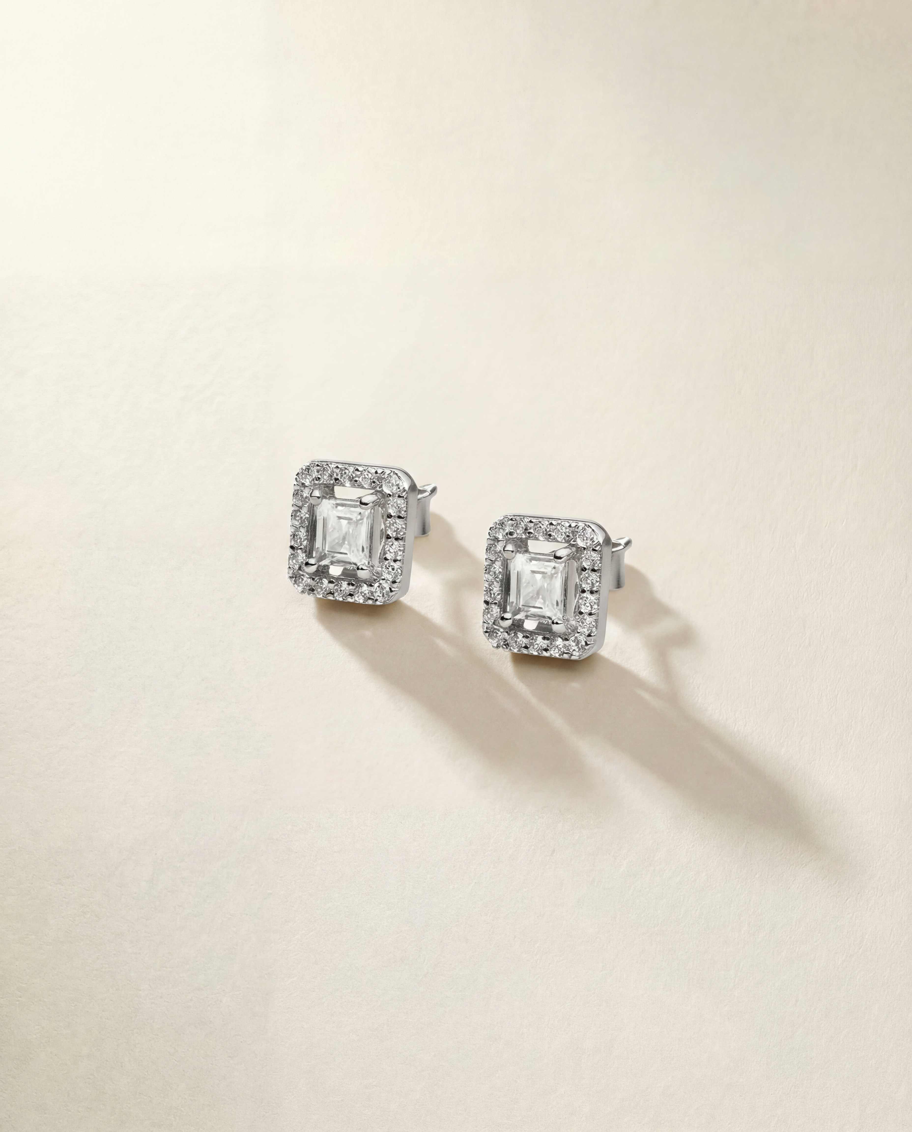 Pair of silver earrings with gemstones on a beige background