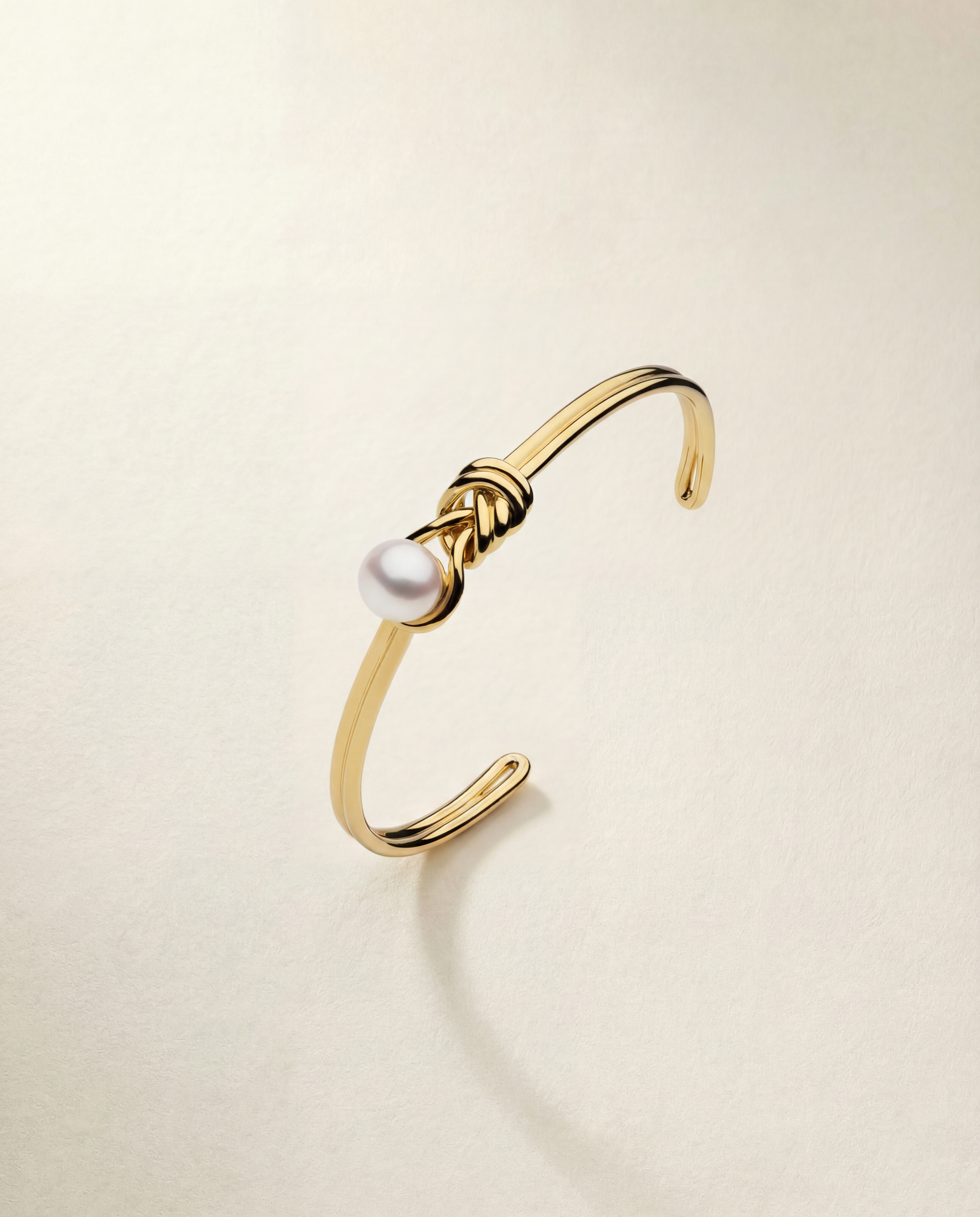 Gold bracelet with a pearl on a beige background