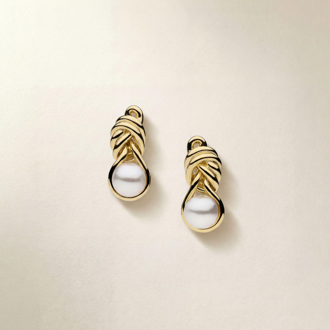 Pair of gold earrings with pearls on a beige background