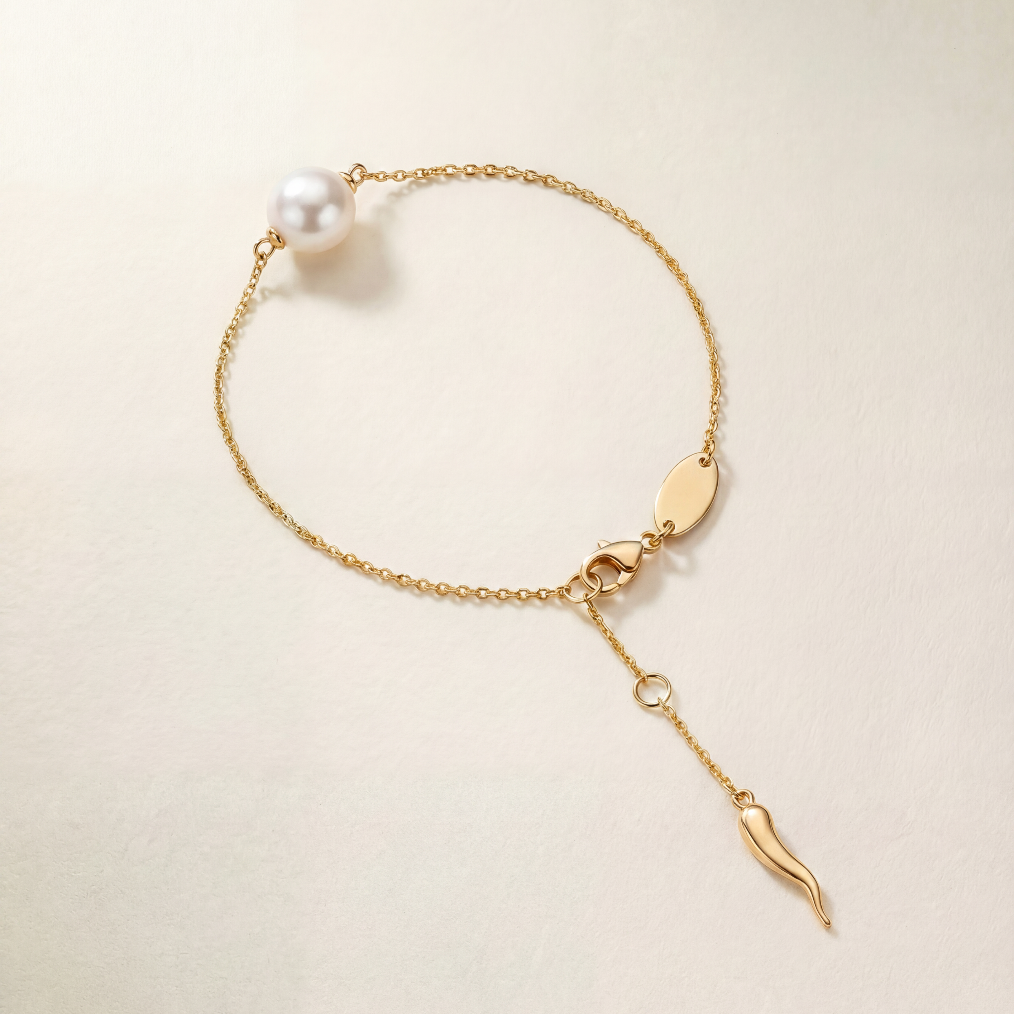 Gold bracelet with a pearl on a light beige background