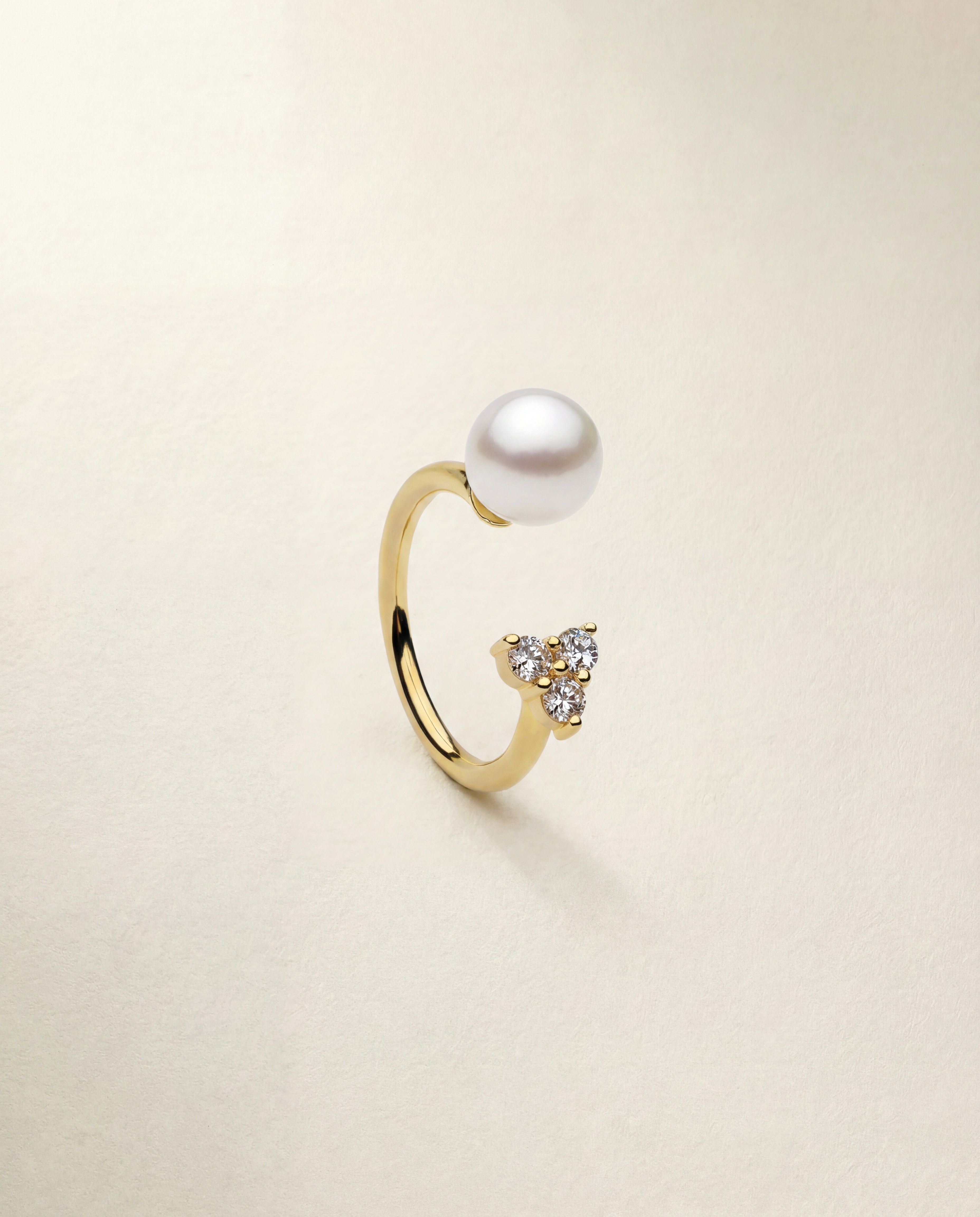 Gold ring with a pearl and small gemstones on a beige background