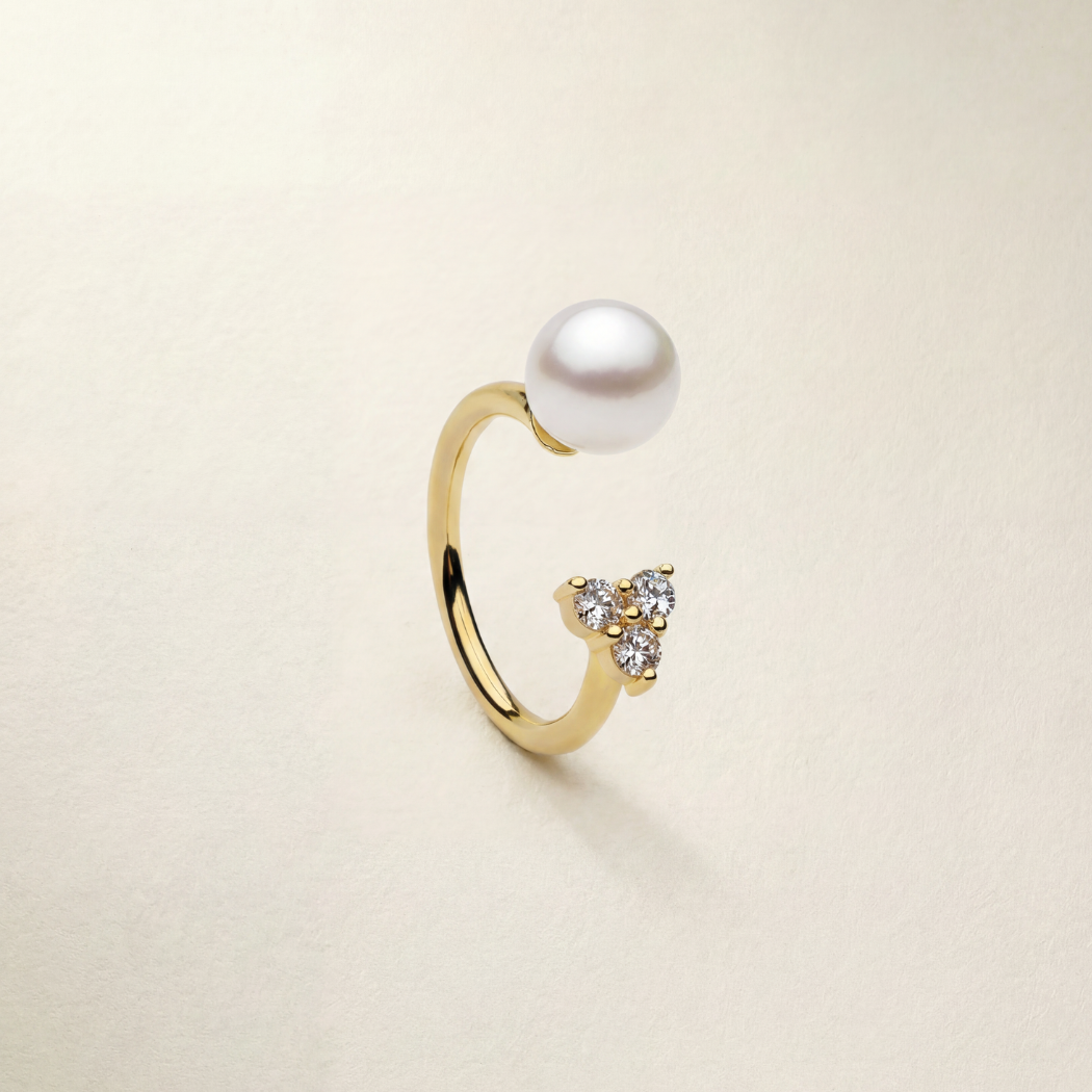 Gold ring with a pearl and small gemstones on a beige background