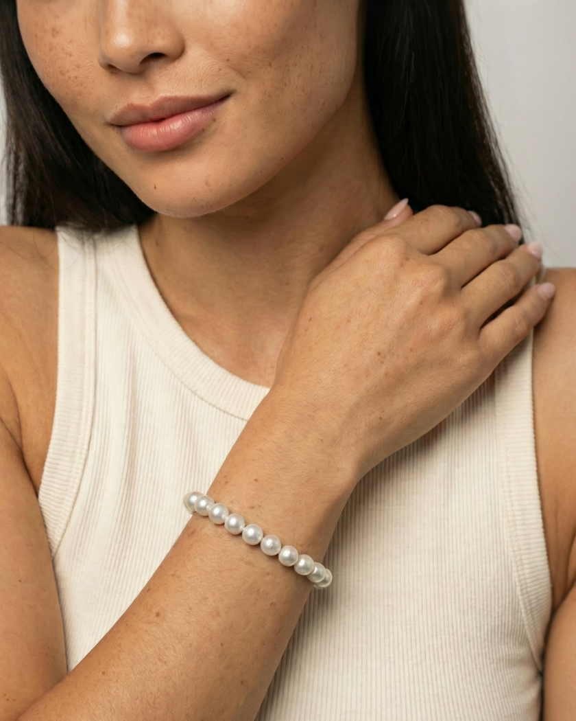 Woman wearing a south sea pearl bracelet on a plain background