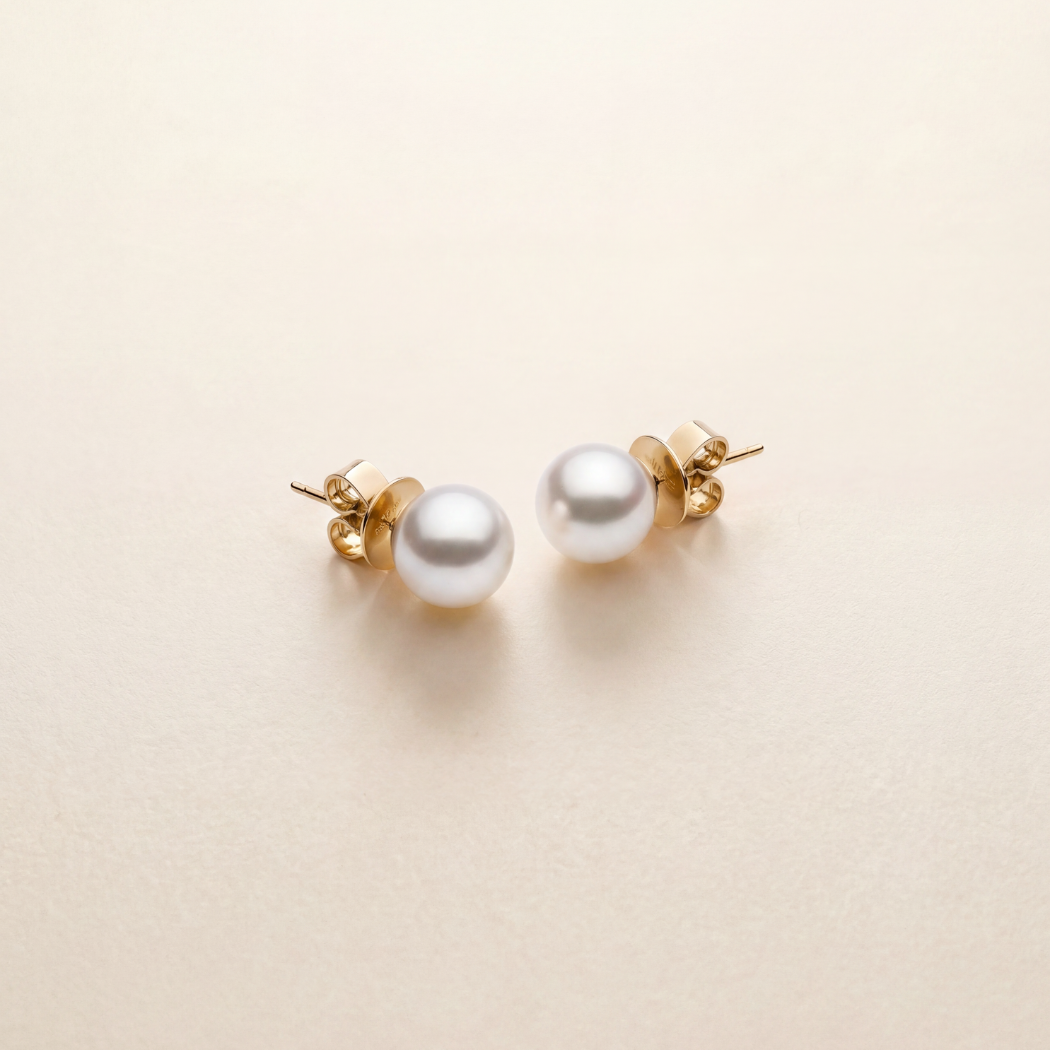 Pearl earrings with gold posts on a light beige background